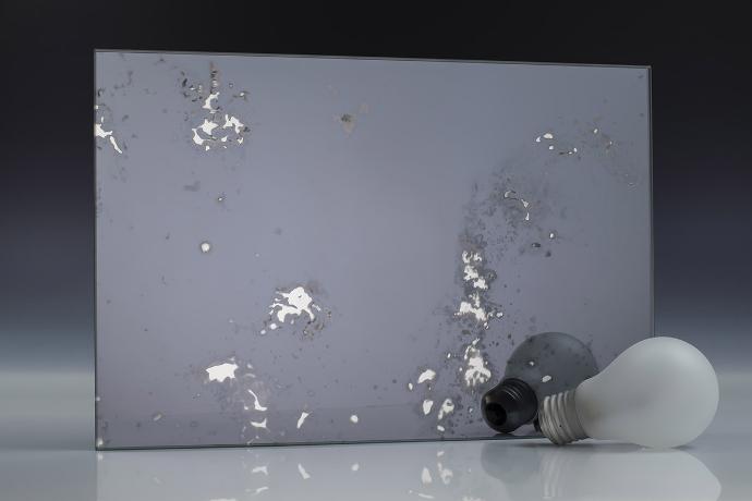 Četverokutni komad sivog ogledala s patinom i žarulja na neutralnoj pozadini