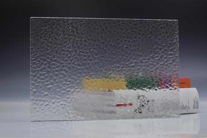 A square piece of clear texture glass and a book on a neutral background