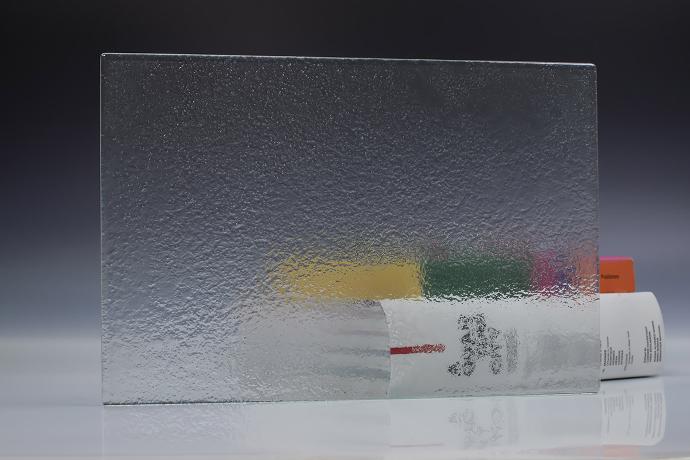 A square piece of clear texture glass and a book on a neutral background