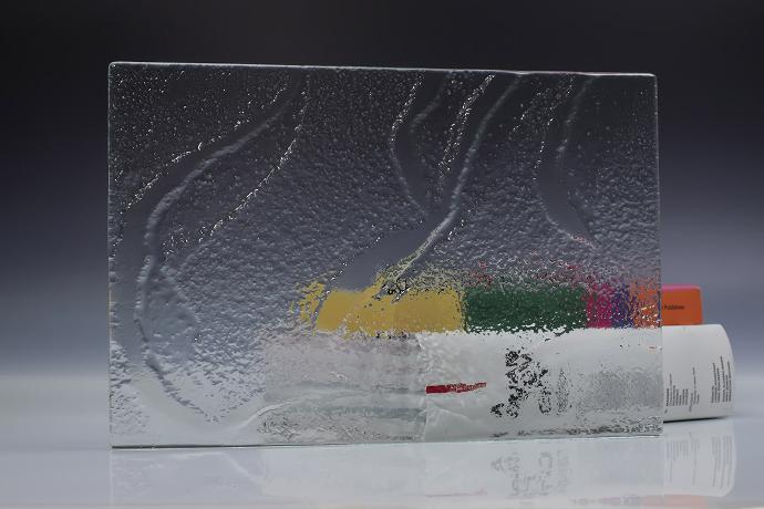 A square piece of clear texture glass and a book on a neutral background