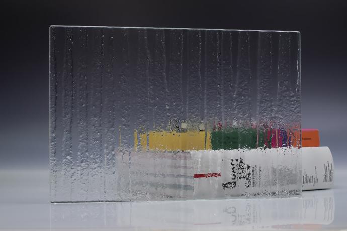 A square piece of clear texture glass and a book on a neutral background