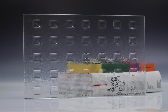 A square piece of clear texture glass and a book on a neutral background