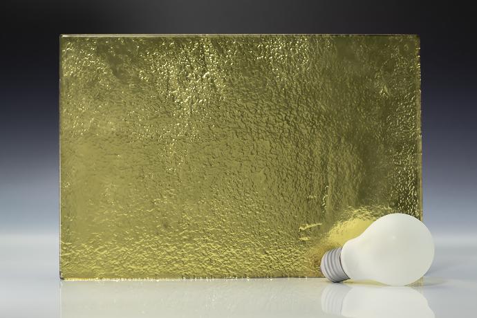Gold - metallic - reljefno staklo - uzorak Četverokutni komad reljefnog stakla zlatne boje i žarulja na neutralnoj pozadini