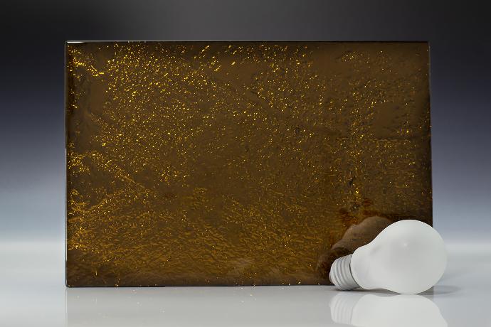 Bronze - metallic - reljefno staklo - uzorak Četverokutni komad reljefnog stakla boje bronce i žarulja na neutralnoj pozadini