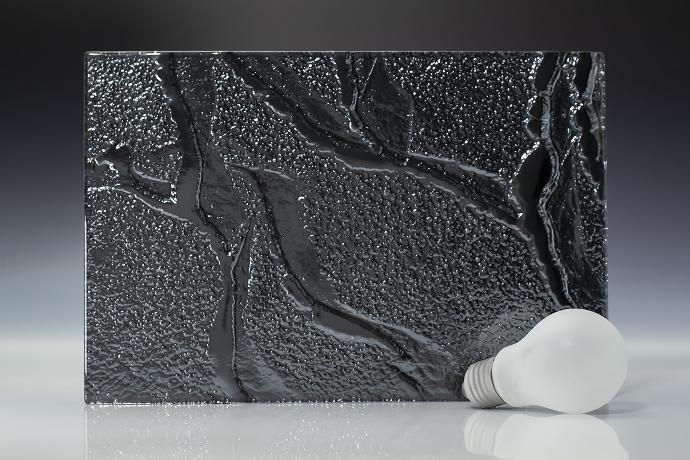 A square piece of dark colored texture glass and a light bulb on a neutral background