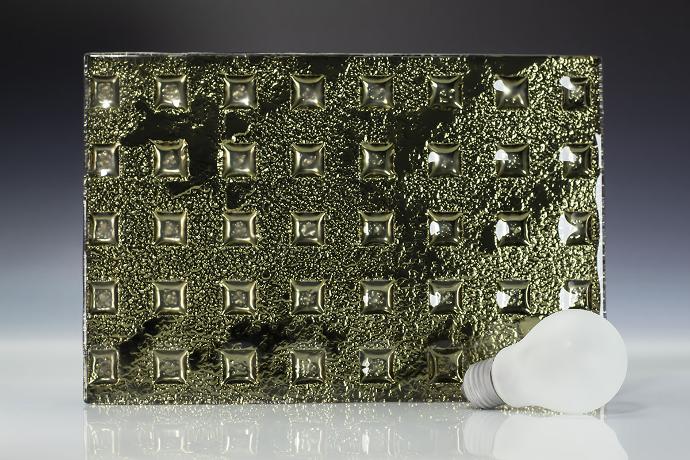 Intaglio moss square - metallic - reljefno staklo - uzorak Četverokutni komad reljefnog stakla zelene boje i žarulja na neutralnoj pozadini