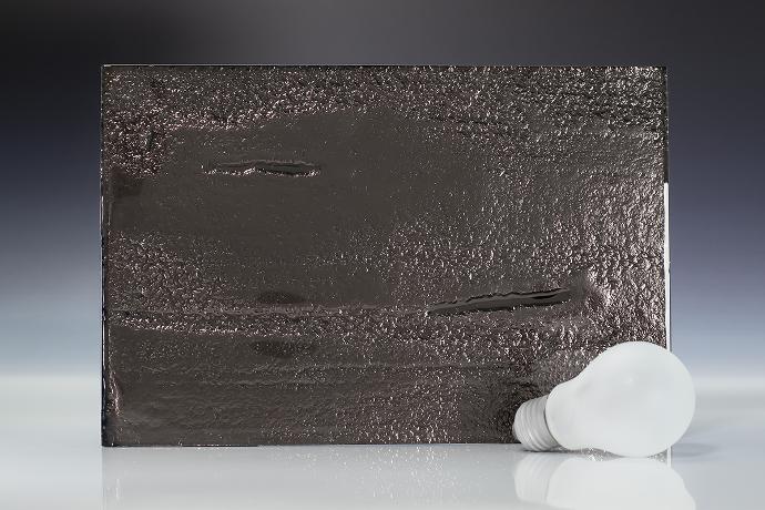 Mercury dust - terrestrial - reljefno staklo - uzorak Četverokutni komad reljefnog stakla sive boje i žarulja na neutralnoj pozadini