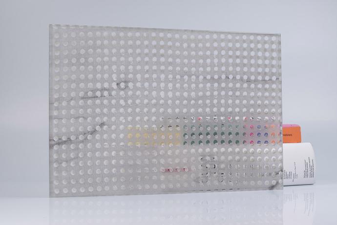 A square piece of glass with grey textiles and books on a neutral background