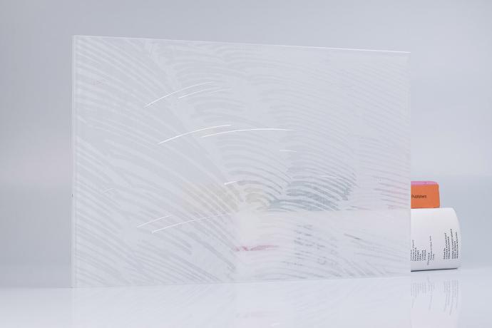 A square piece of glass with a white textile and books on a neutral background