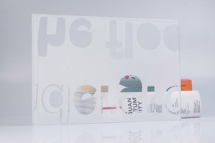 Četverokutni komad stakla s bijelim tekstilom sa slovima i knjige na neutralnoj pozadini