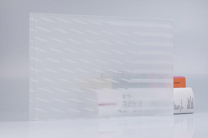 A square piece of glass with a white pattern and books on a neutral background