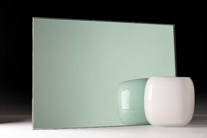 A square piece of green mirror and a bowl on a dark background