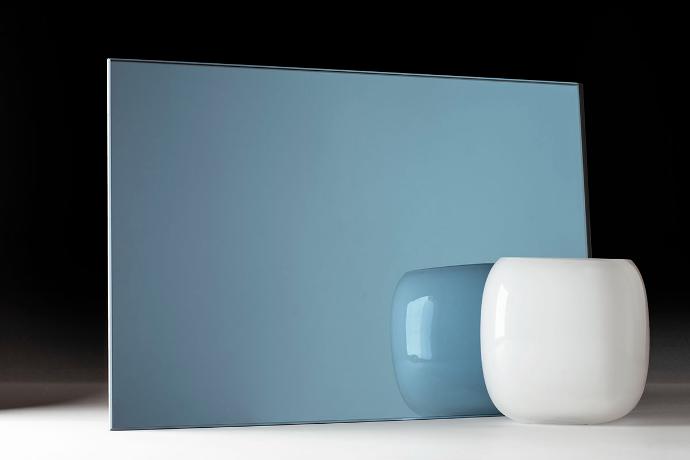 A square piece of mirror in blue and a bowl on a dark background