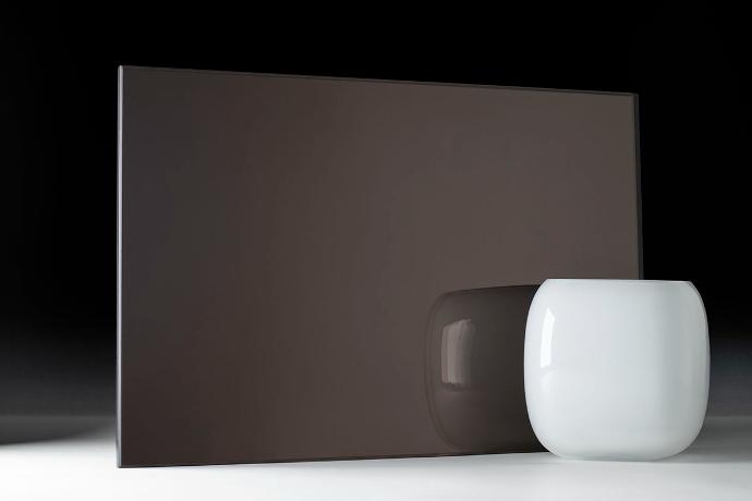 A square piece of dark brown mirror and a bowl on a dark background