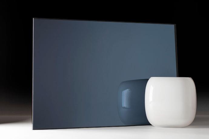 A square piece of dark blue mirror and a bowl on a dark background