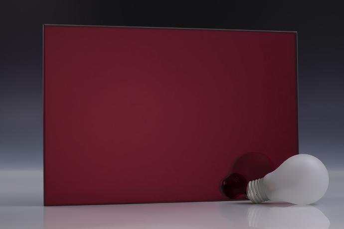 A rectangular piece of dark red mirror and book on a neutral background