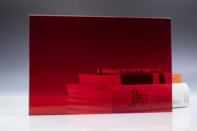 A square piece of red transparent glass and a book on a neutral background