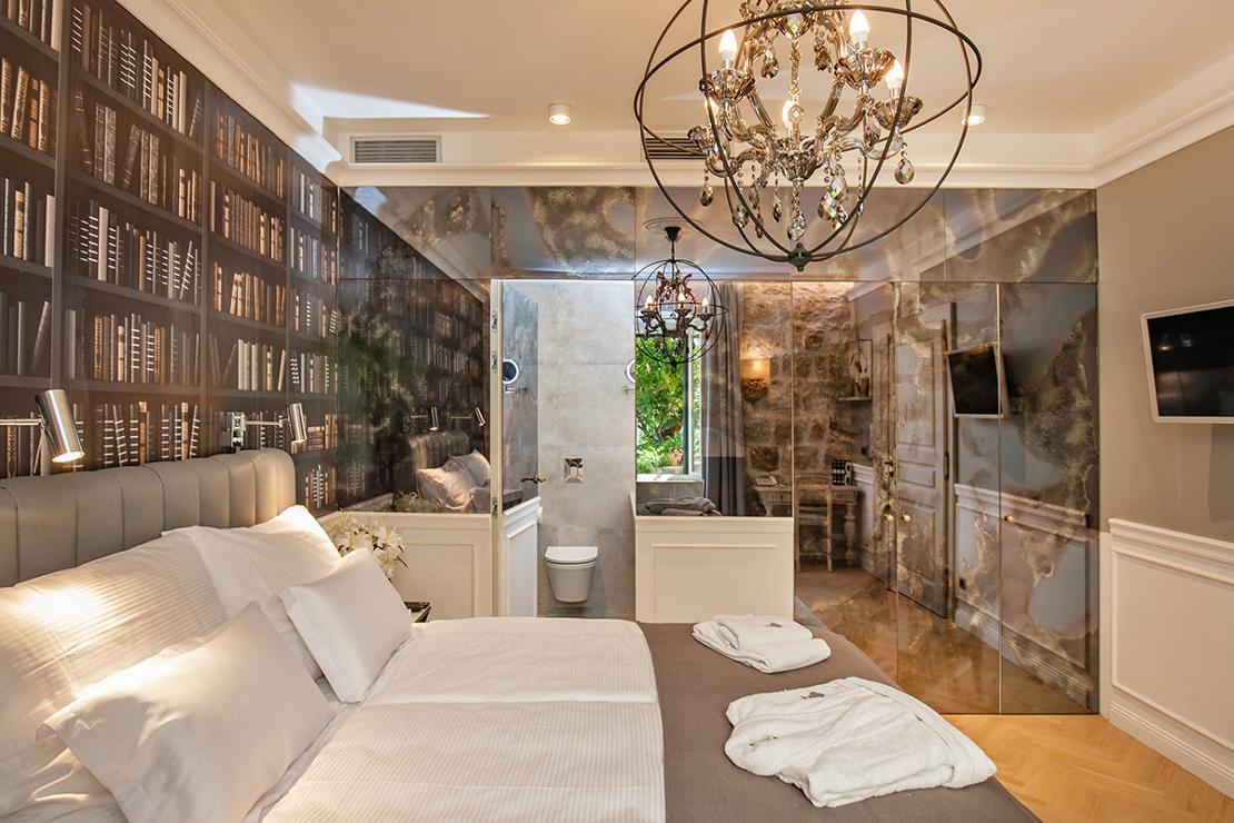 Luksuzni interijer spavaće sobe s antiknim ogledalima, krevetom i lusterom
