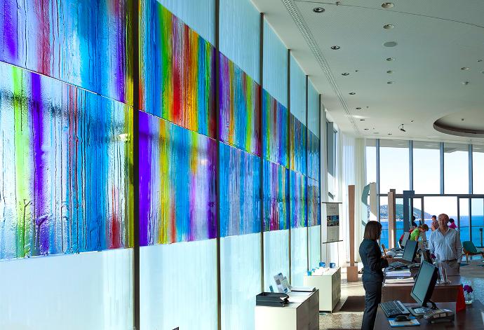 A glass wall painted in vivid colors and people in the background
