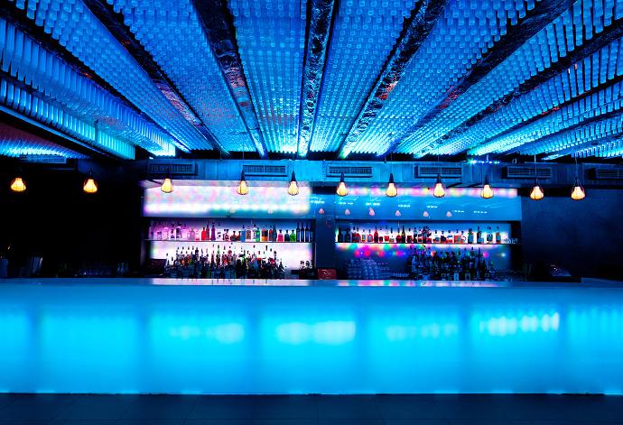 A glass bar in a modern interior, illuminated by blue light