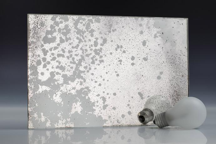 Heavy silver-white oxide - silver oxidation - antique mirror - sample A square piece of mirror with a patina effect and light bulbs on a neutral background