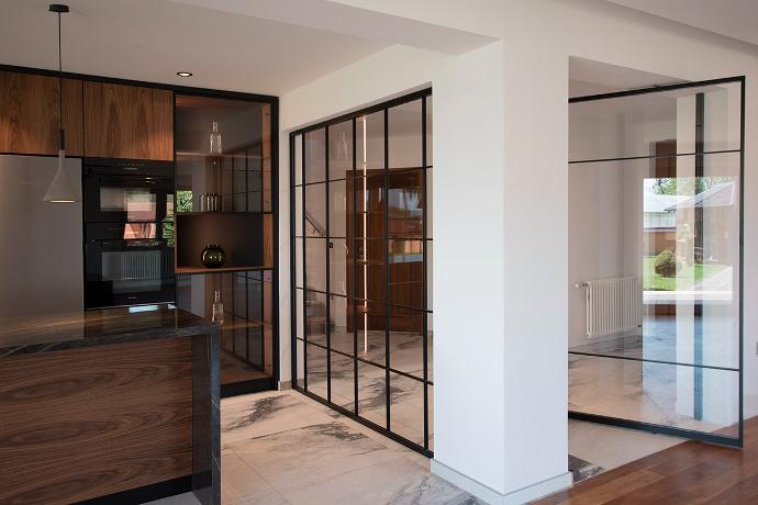 Interior of modern kitchen with glass partition and door.