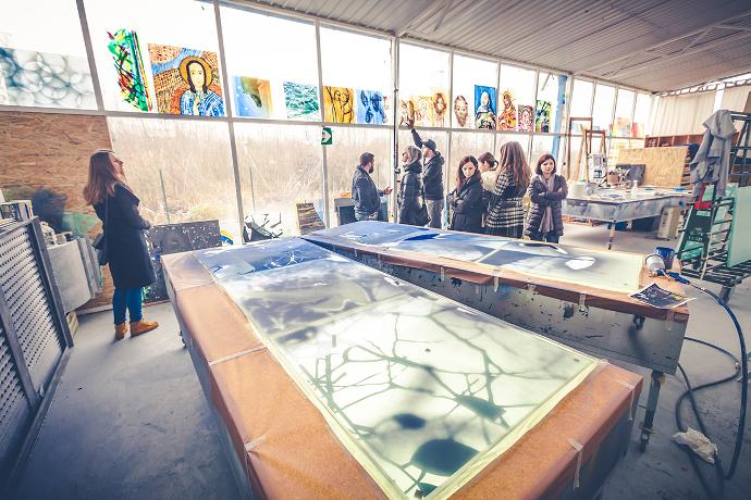 A group of people in an art workshop, surrounded by paintings.