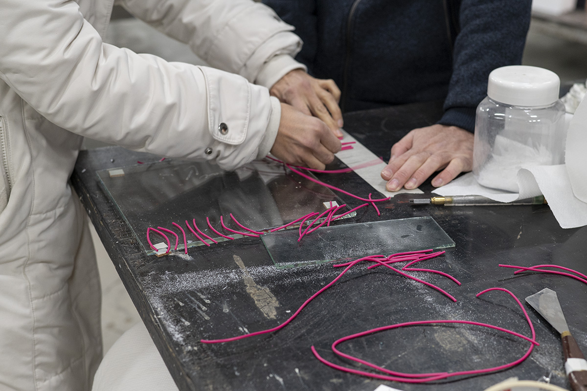 Two people around a workbench with different materials and tools.