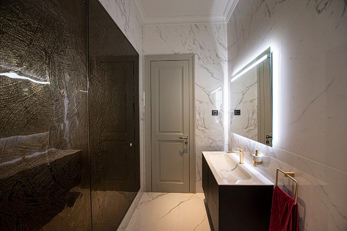 Luxuriously designed toilet with glass wall paneling, door, mirror, bathroom element with sink and towel