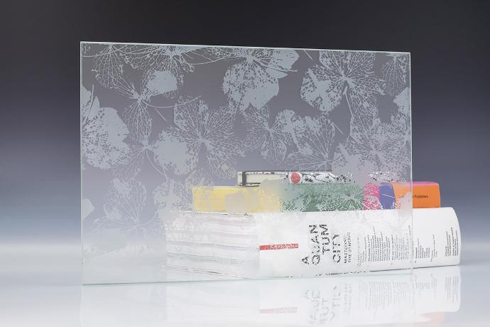 A square piece of etch glass with a floral pattern and books on a neutral background