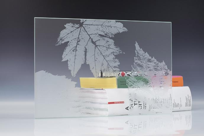 Četverokutni komad pjeskarenog stakla s floralnim uzorkom i knjige na neutralnoj pozadini