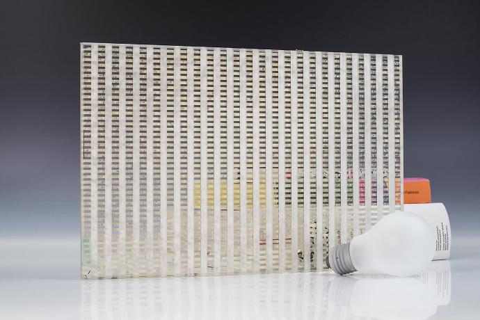 A square piece of etch mirror with a linear pattern, a light bulb and books on a neutral background