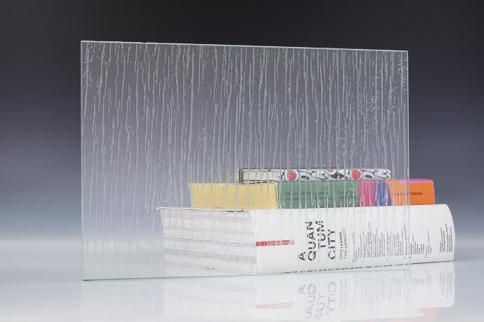 A square piece of etch glass with an irregular pattern and books on a neutral background