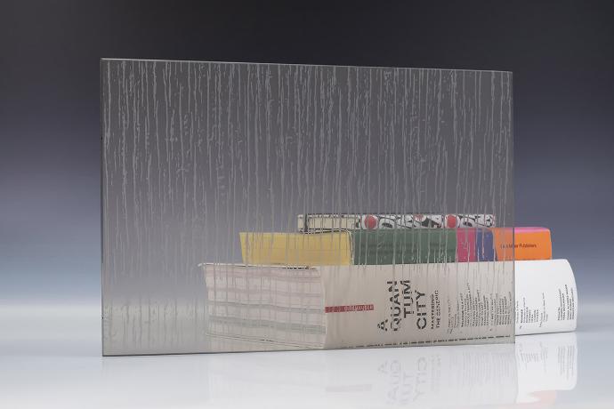 Četverokutni komad pjeskarenog stakla s nepravilnim uzorkom i knjige na neutralnoj pozadini