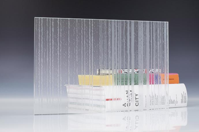 A square piece of patterned etch glass and books on a neutral background