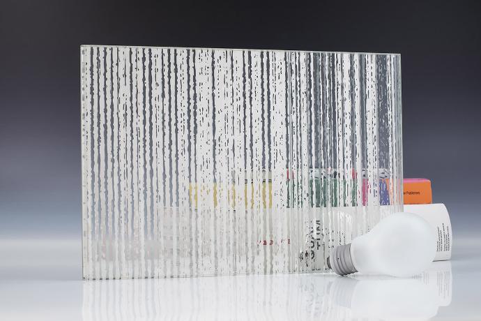 A square piece of patterned etch glass, a light bulb and books on a neutral background