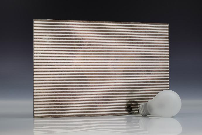 A square mirror piece with a linear pattern, a light bulb and books on a neutral background