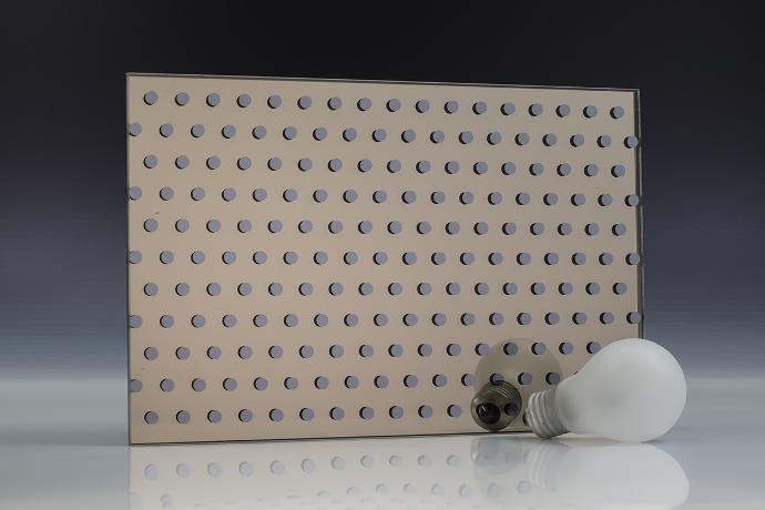 A square piece of gray mirror with a dot pattern and a light bulb on a neutral background