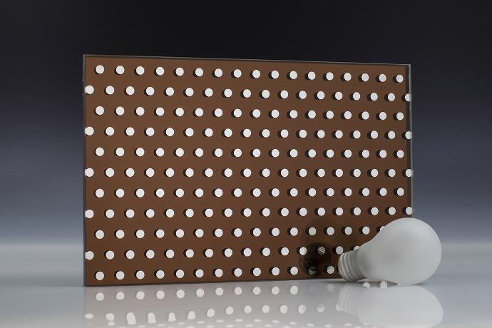A square piece of brown mirror with a dot pattern and a light bulb on a neutral background