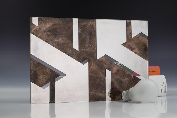 A square mirror piece with a geometric pattern, a light bulb and books on a neutral background
