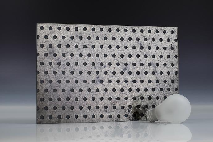 A square piece of gray mirror with a dot pattern and a light bulb on a neutral background