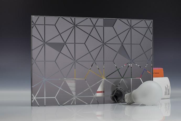 A square piece of gray mirror with a hexagon pattern, light bulbs and books on a neutral background