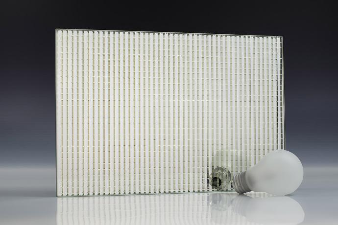 A square mirror piece with a linear pattern and a light bulb on a neutral background