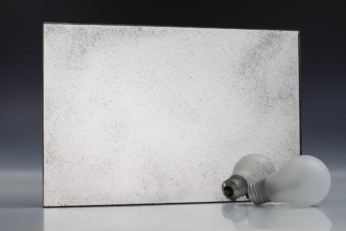 Silver fine grain - silver oxidation - antique mirror - sample A square piece of mirror with a patina effect and light bulbs on a neutral background